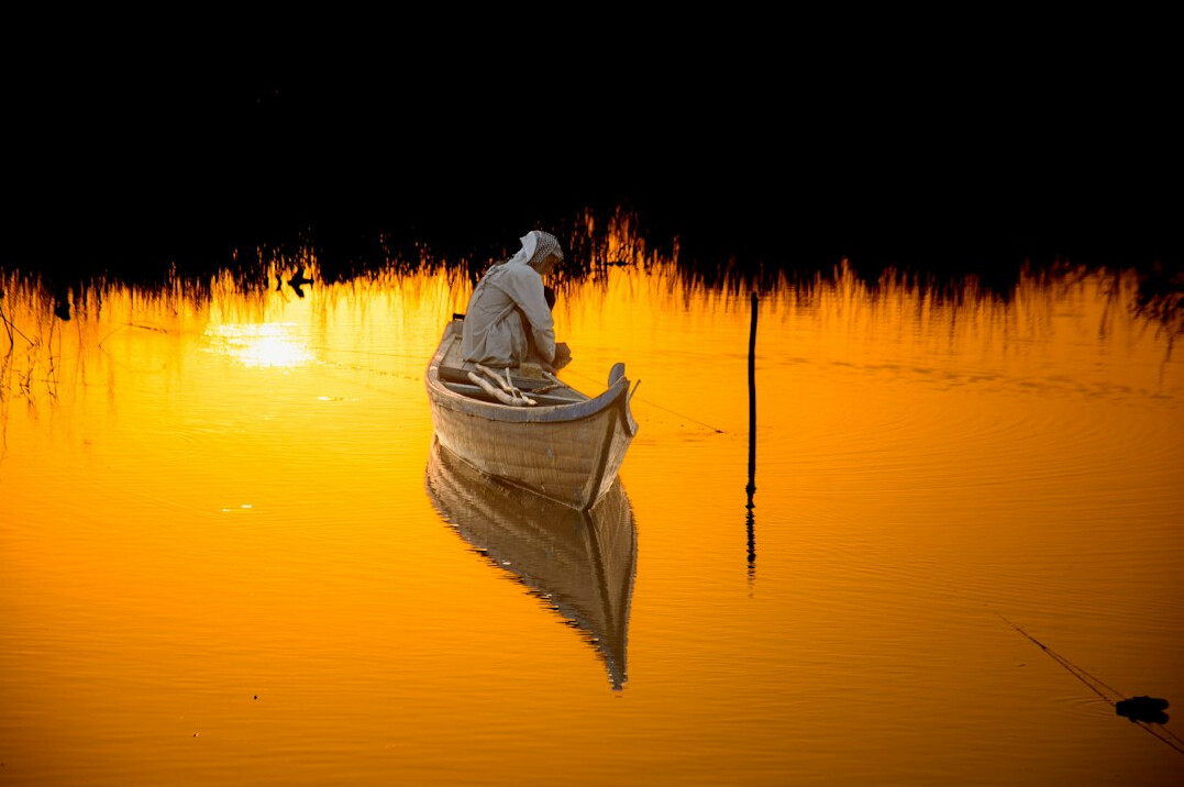 person meditating by lake